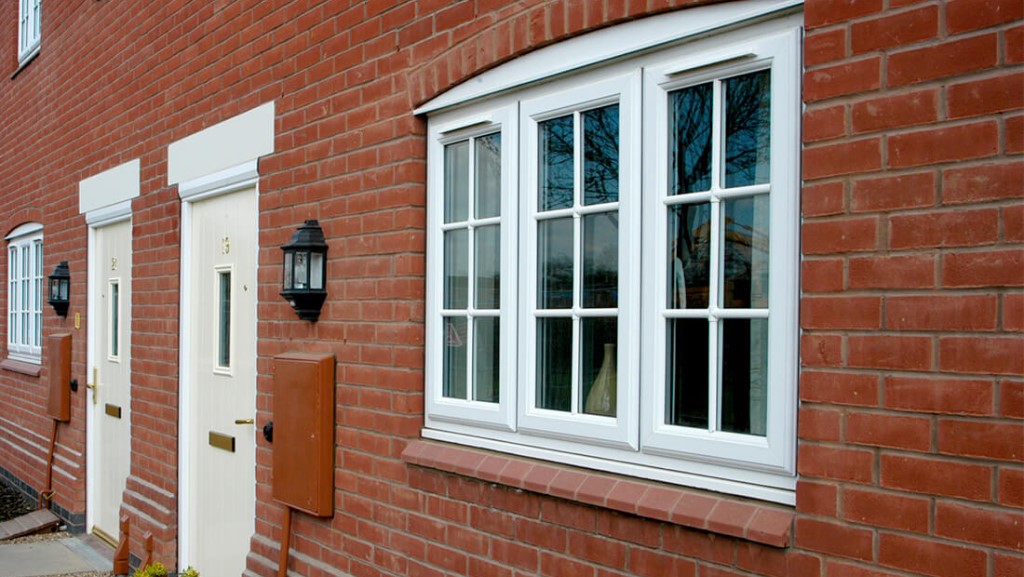 a photograph of a row of red brick terraced houses, with white upvc doors and casement windows with trickle vents in